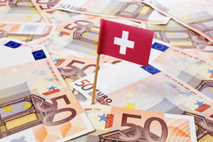 Drapeau suisse au milieu des billets de 50 euros illustre le guide fiscal pour les travailleurs frontaliers suisses.