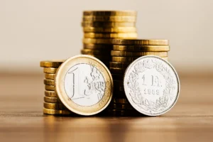 Pièces de monnaie euro et franc suisse empilées, illustrant la double imposition France Suisse