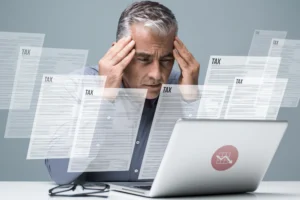 Homme concentré devant un ordinateur avec des formulaires fiscaux illustrant la déclaration d’impôt suisse